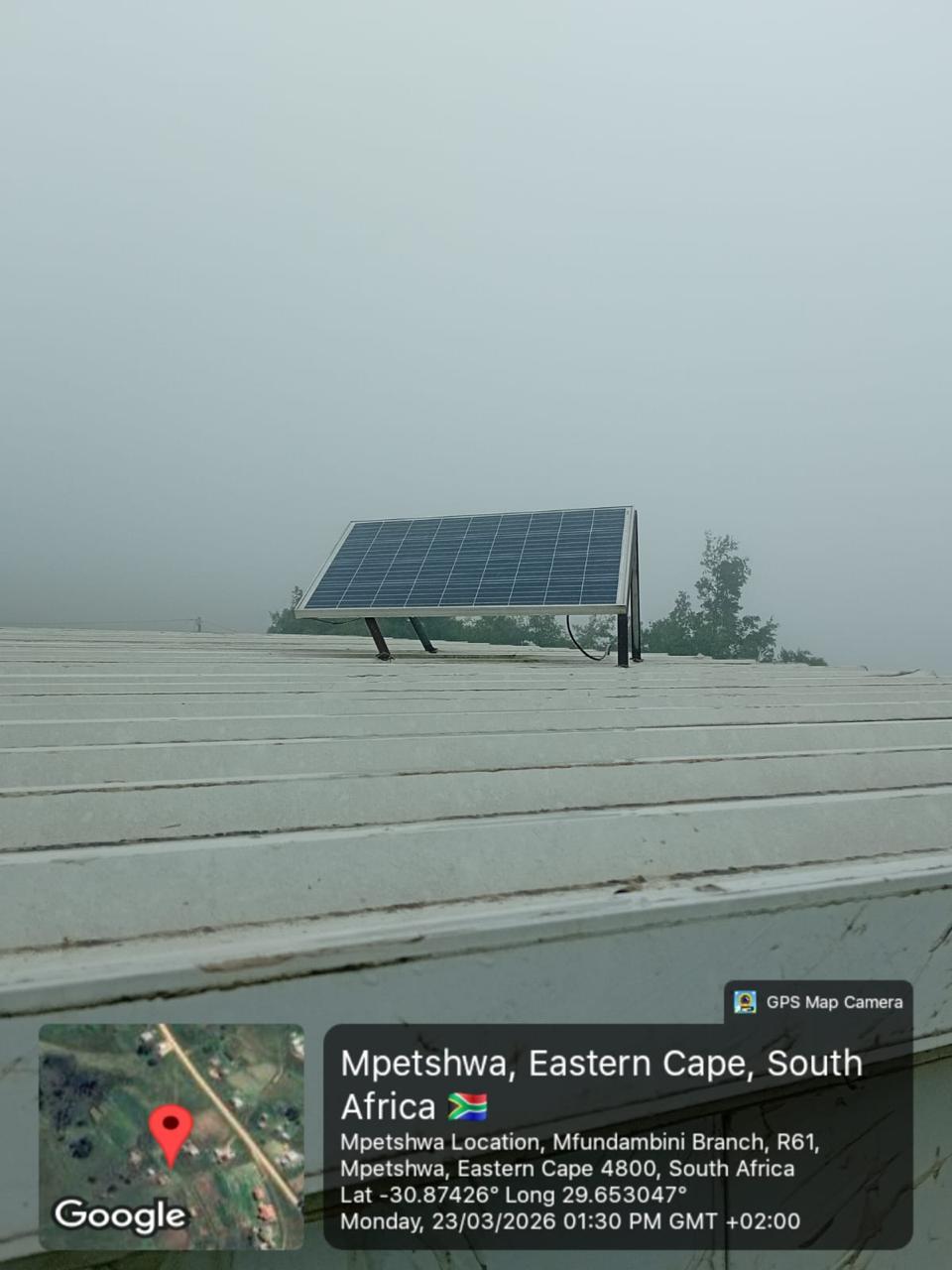 Distant rooftop solar panel shown against an overcast sky.